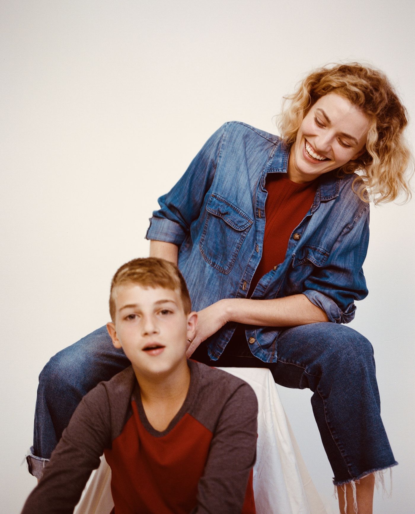 The mother laughs, perched behind her older son.